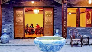 Un restaurante chino tradicional con puertas de madera y un gran jarrón azul de cerámica en primer plano.