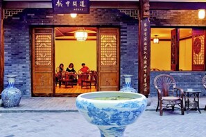 A traditional Chinese restaurant with wooden doors and a large blue ceramic vase in the foreground. - Shaoxing Dayue Xiaoyuan Culture Theme Hotel (Lu Xun's hometown Shenyuan Branch) (Shaoxing)