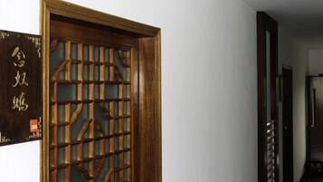 Une porte en bois ornée d’un motif de treillis complexe, un couloir au plancher sombre et une enseigne fixée au mur avec du texte.