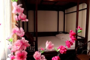 Una habitación tradicional con cama, muebles de madera y ventana con cortinas.