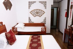 Une chambre d’hôtel avec un lit en bois, un élément décoratif mural et un tapis rouge à motifs.