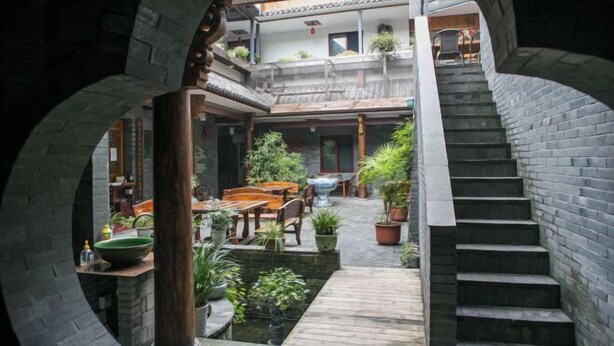 A courtyard with a wooden staircase, stone walls, and potted plants. - Shaoxing Dayue Xiaoyuan Culture Theme Hotel (Lu Xun's hometown Shenyuan Branch) (Shaoxing)