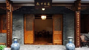 A traditional Chinese building entrance with wooden doors, a signboard, and two vases. - Shaoxing Dayue Xiaoyuan Culture Theme Hotel (Lu Xun's hometown Shenyuan Branch) (Shaoxing)