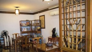 A traditional room with wooden furniture, a fan, and a bookshelf. - Shaoxing Dayue Xiaoyuan Culture Theme Hotel (Lu Xun's hometown Shenyuan Branch) (Shaoxing)
