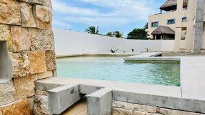 Una piscina amb mur de pedra i una font.