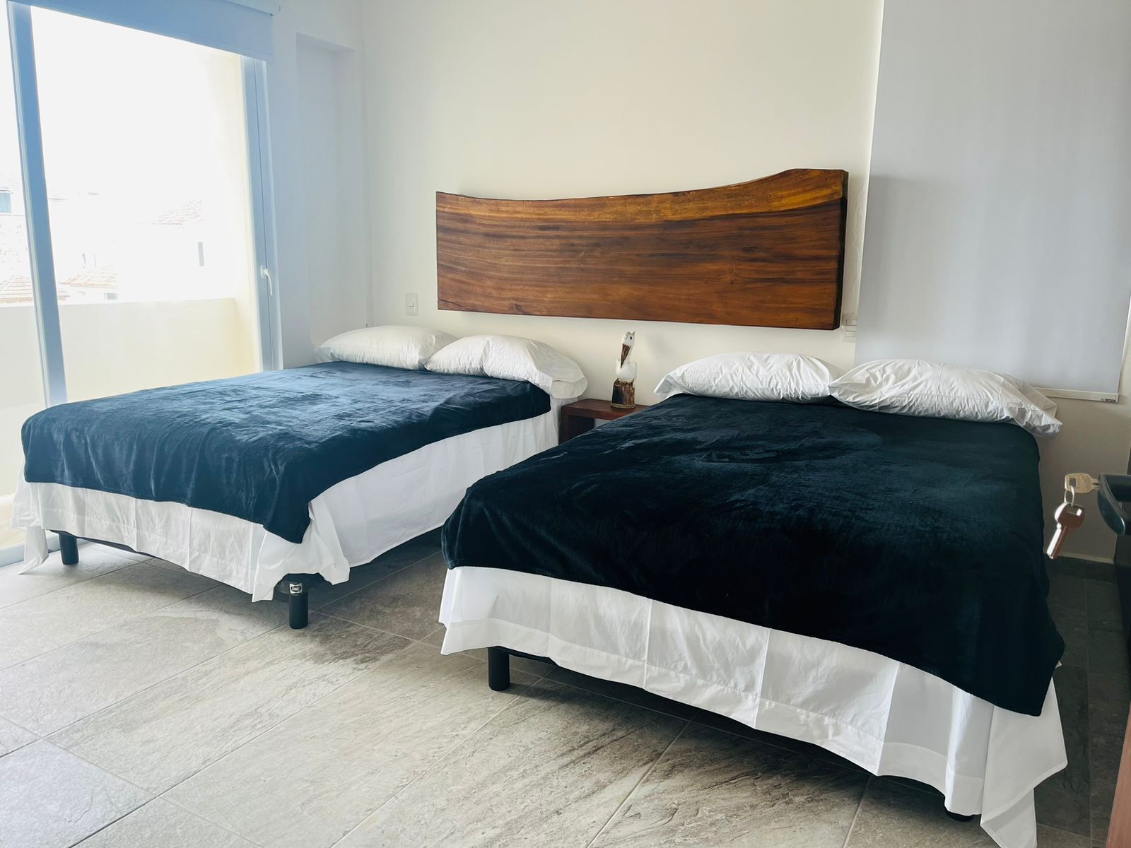 Una camera d'albergo con due letti, un poggiatesta in legno e vista attraverso una porta in vetro.