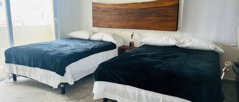 A hotel room with two beds, a wooden headboard, and a view through a glass door.