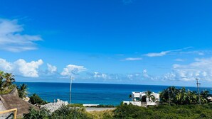 Vista costera amb un cel blau clar, una mar tranquil·la i un edifici blanc de disseny modern.
