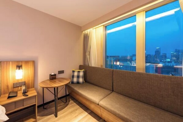 A modern hotel room with a sofa, a small round table, and a nightstand. - Homeinn Plus Hotel (Beijing Jianguomen Capital Pediatric Institute) (Beijing)