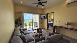 A living room with a sofa, a coffee table, and a TV. There is a balcony with a view of the ocean. - La Diosa Condos holiday apartment (Isla Mujeres)