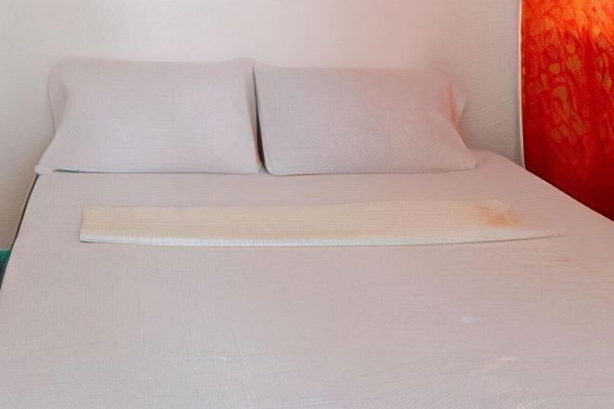 Un lit avec deux oreillers et une tête de lit en bois.