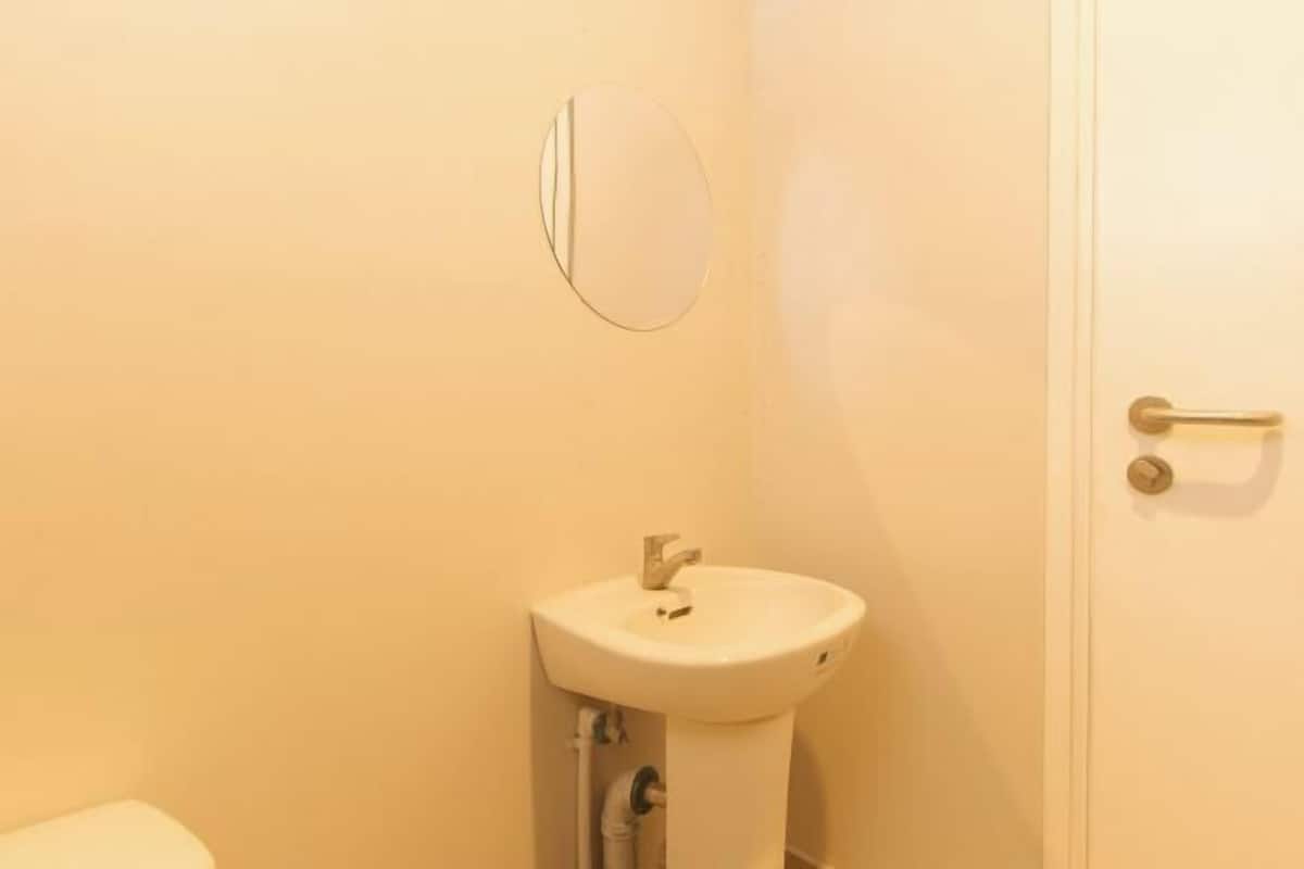 A bathroom with a white sink, a mirror, and a door with a handle.