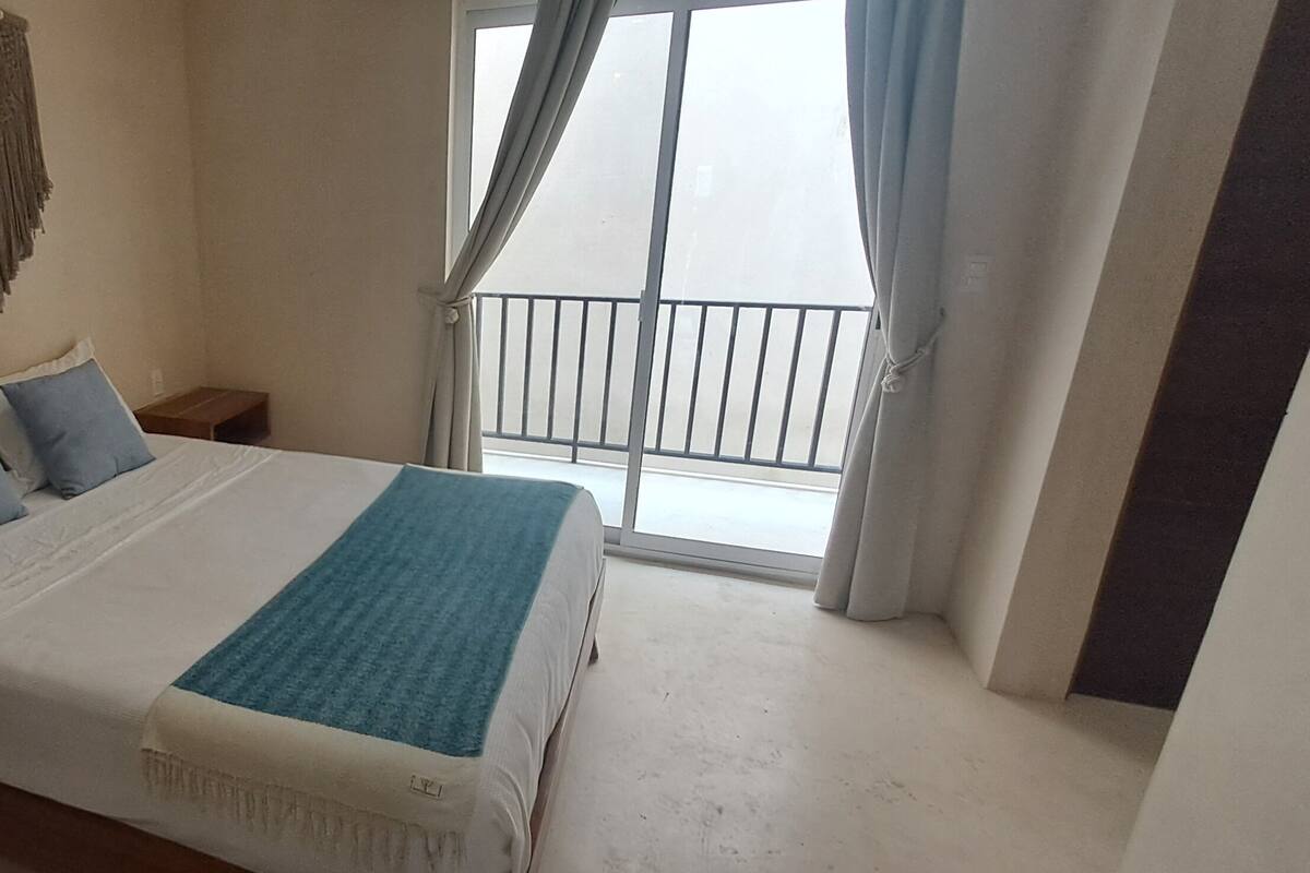 Une chambre à coucher avec un lit, des tables de chevet, une décoration murale et une vue sur un balcon.