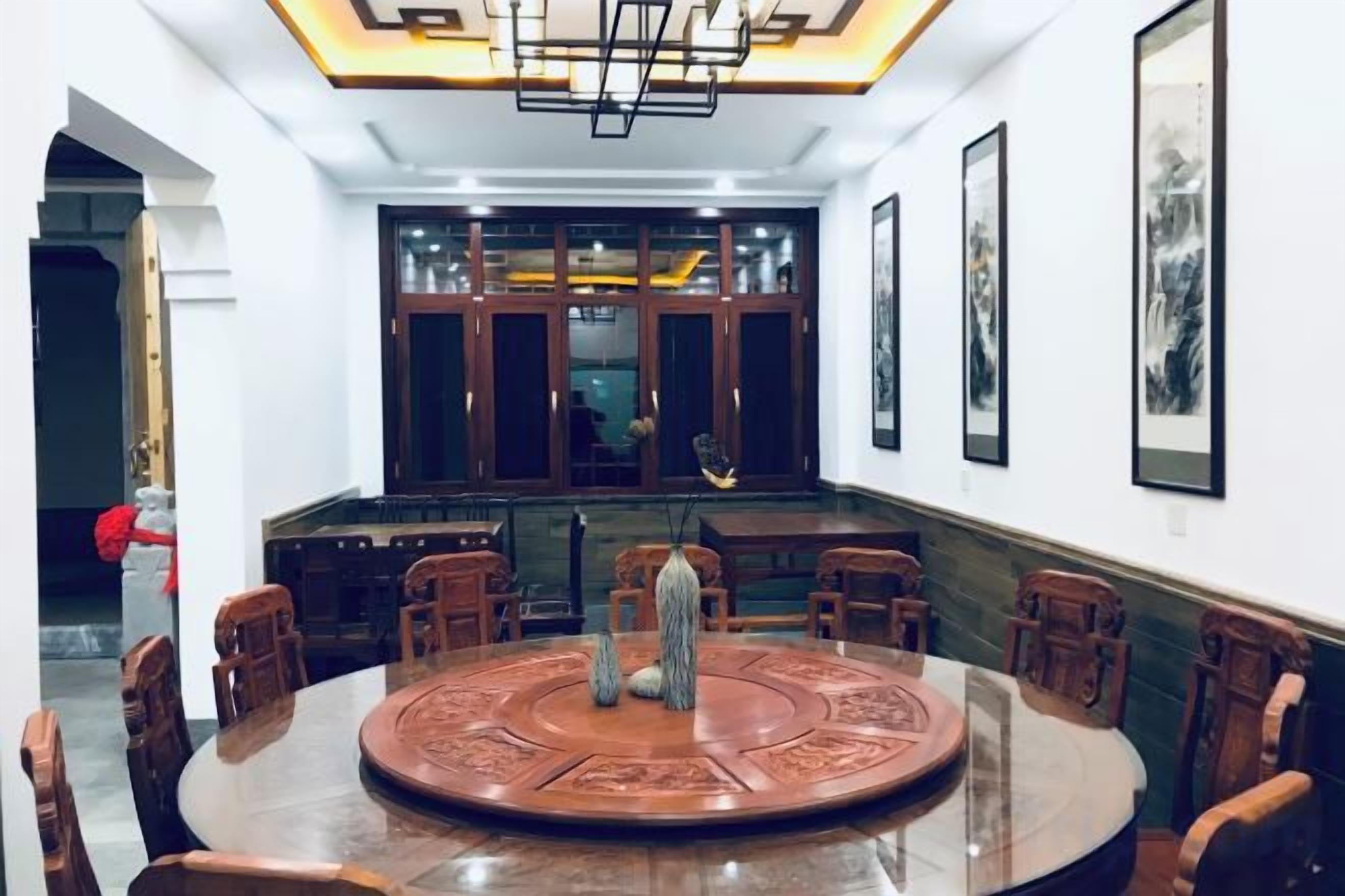 A dining area with a round table, chairs, and a chandelier.