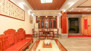 A traditional-style room with a wooden ceiling, a dining table with chairs, a bench, and a large framed calligraphy piece on the wall. - Jiuhuashan Huimo Jiudu Hotel (Qingyang)