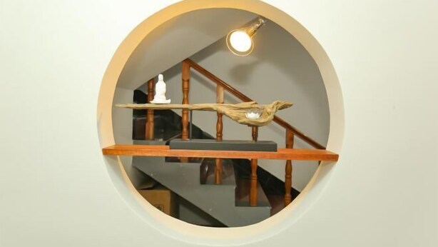A circular mirror with a wooden frame, reflecting a staircase with a wooden railing and a light fixture above. - Jiuhuashan Huimo Jiudu Hotel (Qingyang)