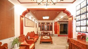 A traditional-style room with wooden furniture, a dining table, and a wall with framed pictures. - Jiuhuashan Huimo Jiudu Hotel (Qingyang)
