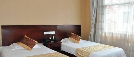 A hotel room with two beds, each with a wooden headboard, a nightstand, and a telephone.