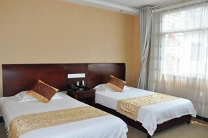 Habitación de hotel con dos camas, cada una con cabecero de madera, mesita de noche y teléfono.