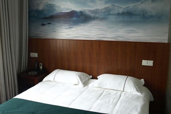 Une chambre d’hôtel avec un lit, une tête de lit en bois et un tableau représentant un paysage marin.