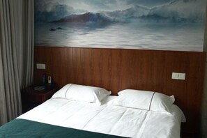 Une chambre d’hôtel avec un lit, une tête de lit en bois et un tableau représentant un paysage marin.