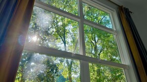 A window with a view of trees and a house in the background. - Inner City Hideout: Serenity with Big Nature Views (Atlanta)