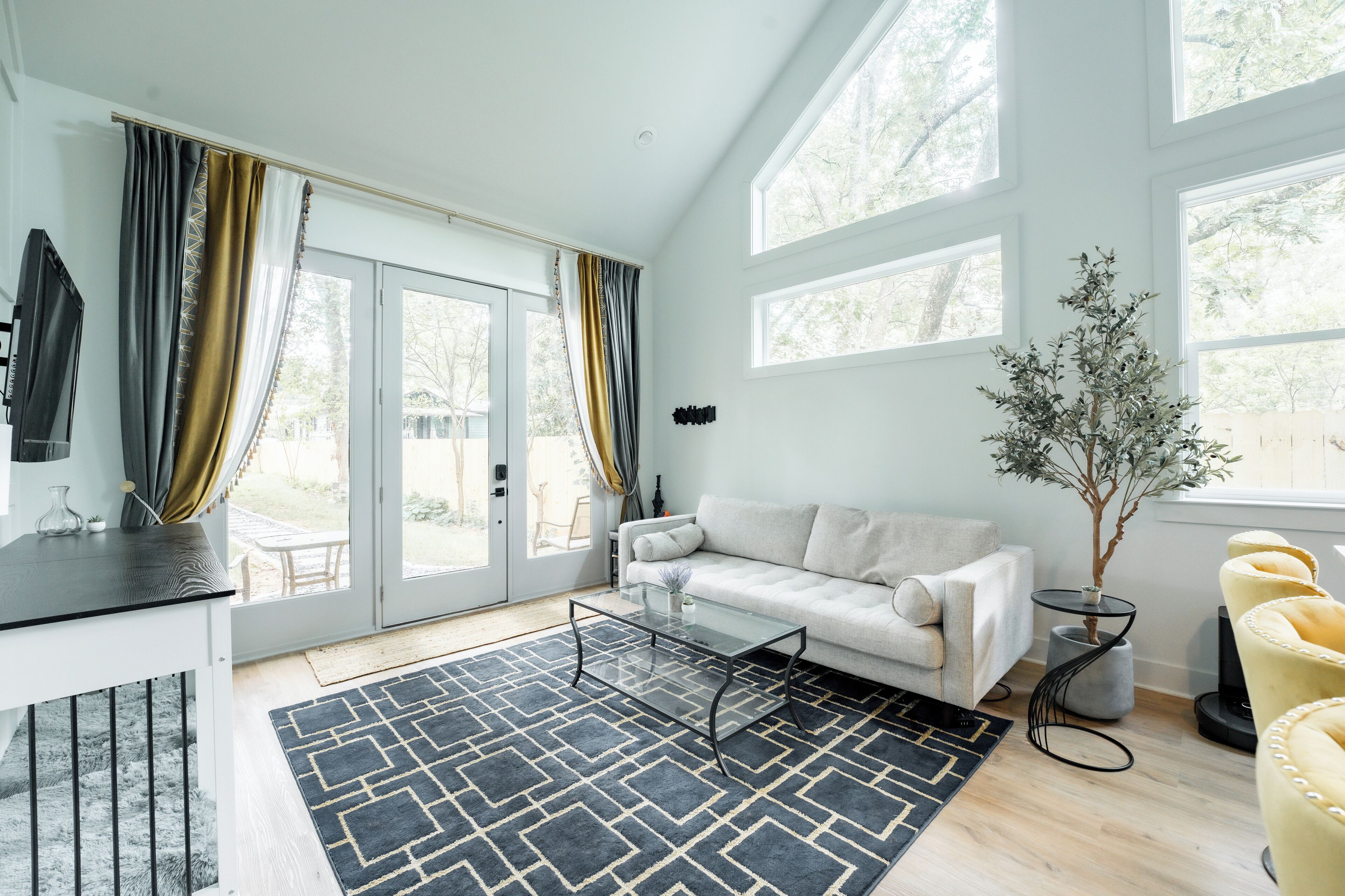 Een moderne woonkamer met een bank, een glazen salontafel en een potplant.