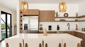 Une cuisine moderne dotée d’un îlot central, de meubles en bois et de luminaires suspendus.