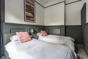 Ein Hotelzimmer mit zwei Betten, einem Nachttisch, einer Lampe und einem großen, abstrakten Gemälde an der Wand.