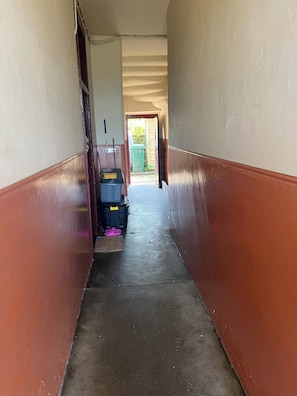 A narrow hallway with a concrete floor and walls painted in two colors.