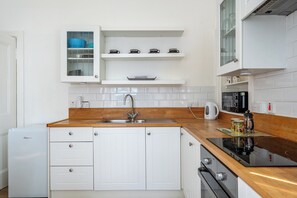 Eine Küche mit weißen Schränken, einer Holz Arbeitsplatte, einer eingebauten Spüle und einer Kaffeemaschine.