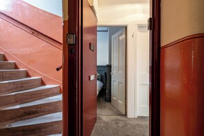 Eine Treppe führt zu einem Raum mit einem Bett und einer Tür.