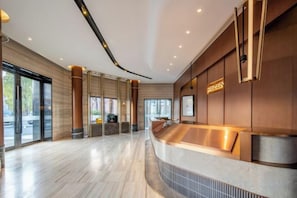 Un vestíbul d'hotel modern amb un taulell de recepció corbat, grans finestres i un sòl net i polit.