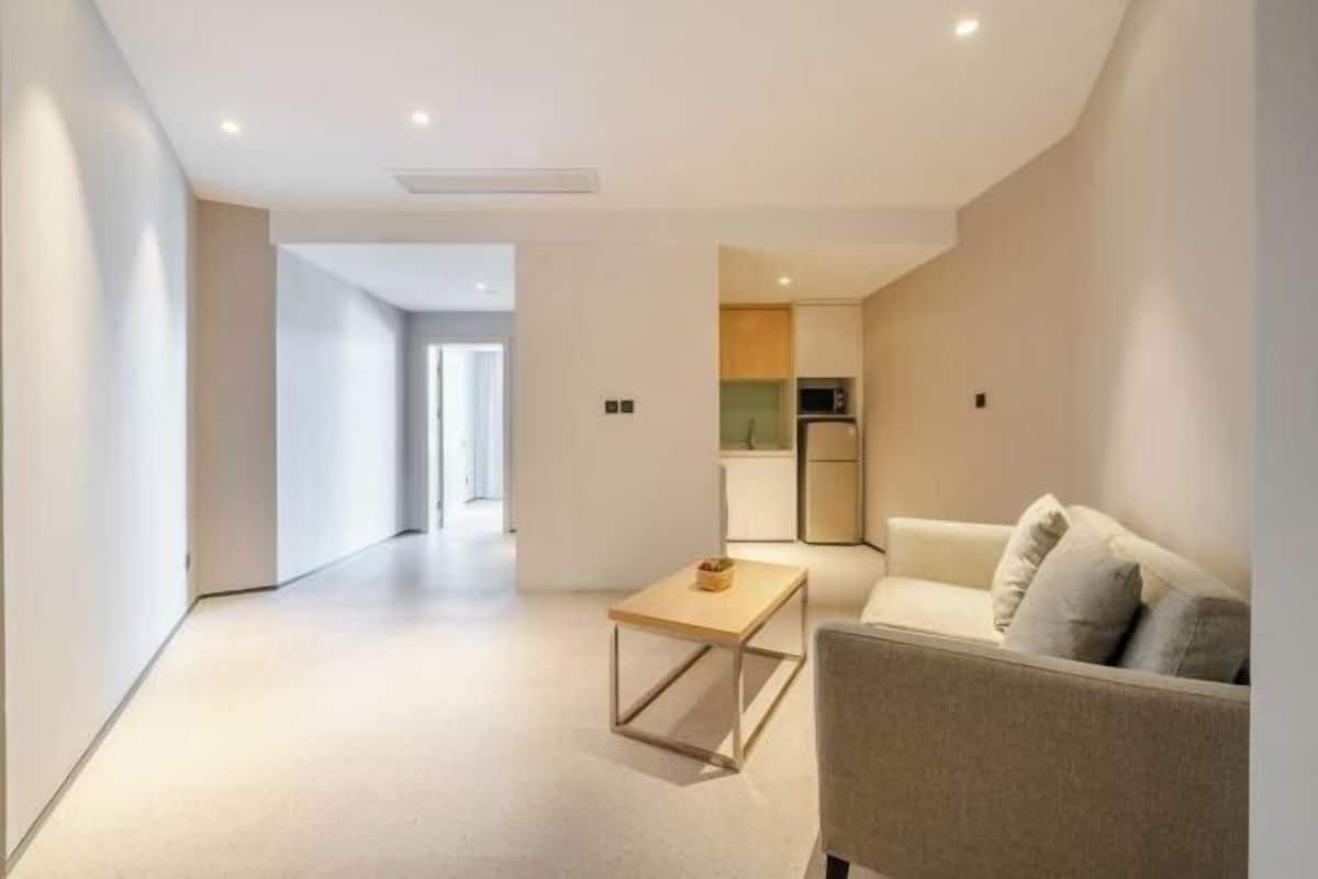 A modern living room with a sofa, a small table, and a kitchen area in the background.