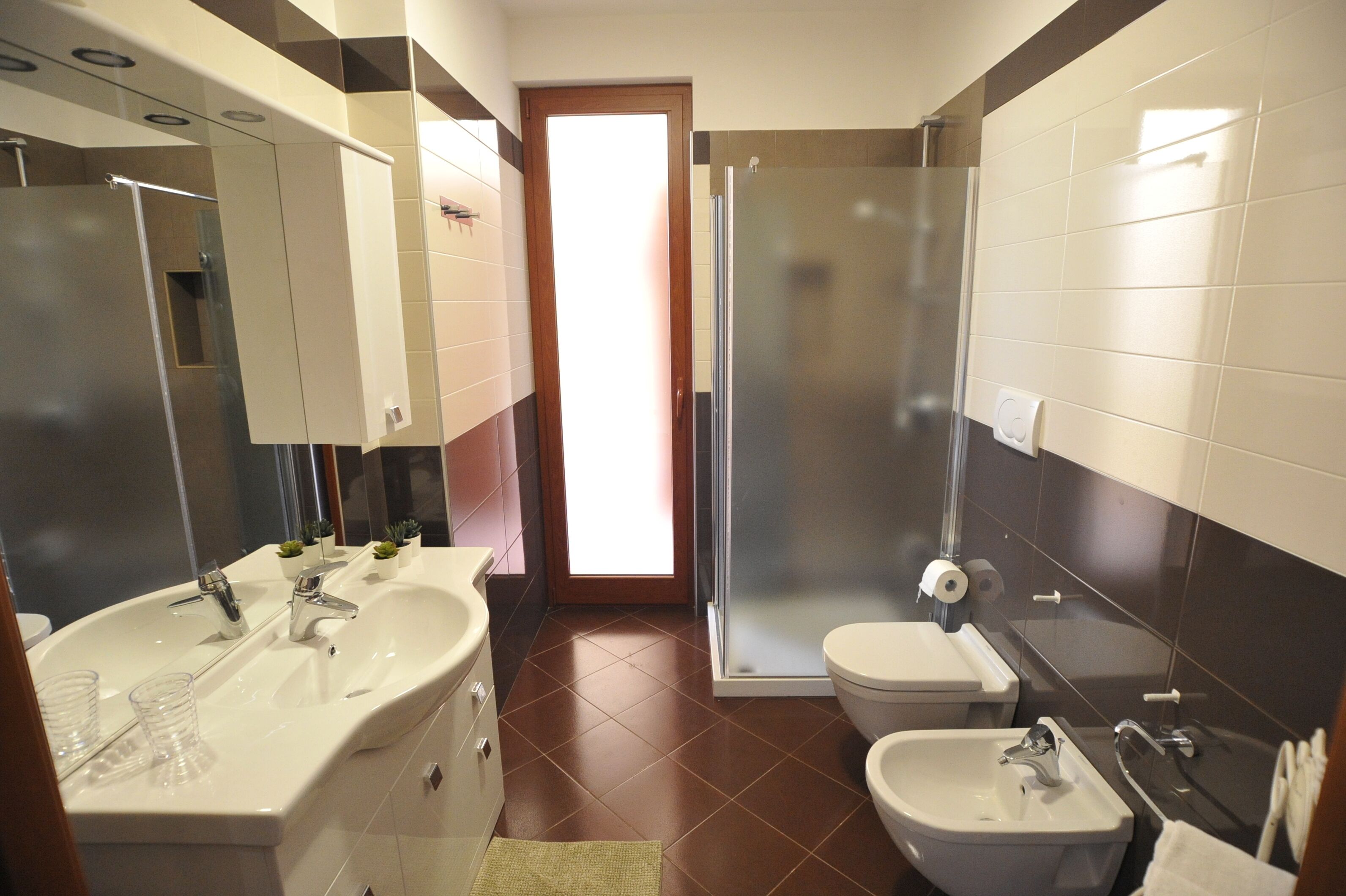A modern bathroom with a shower, toilet, and two sinks.