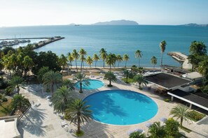 Un resort con una gran piscina, palmeras y vistas al océano.
