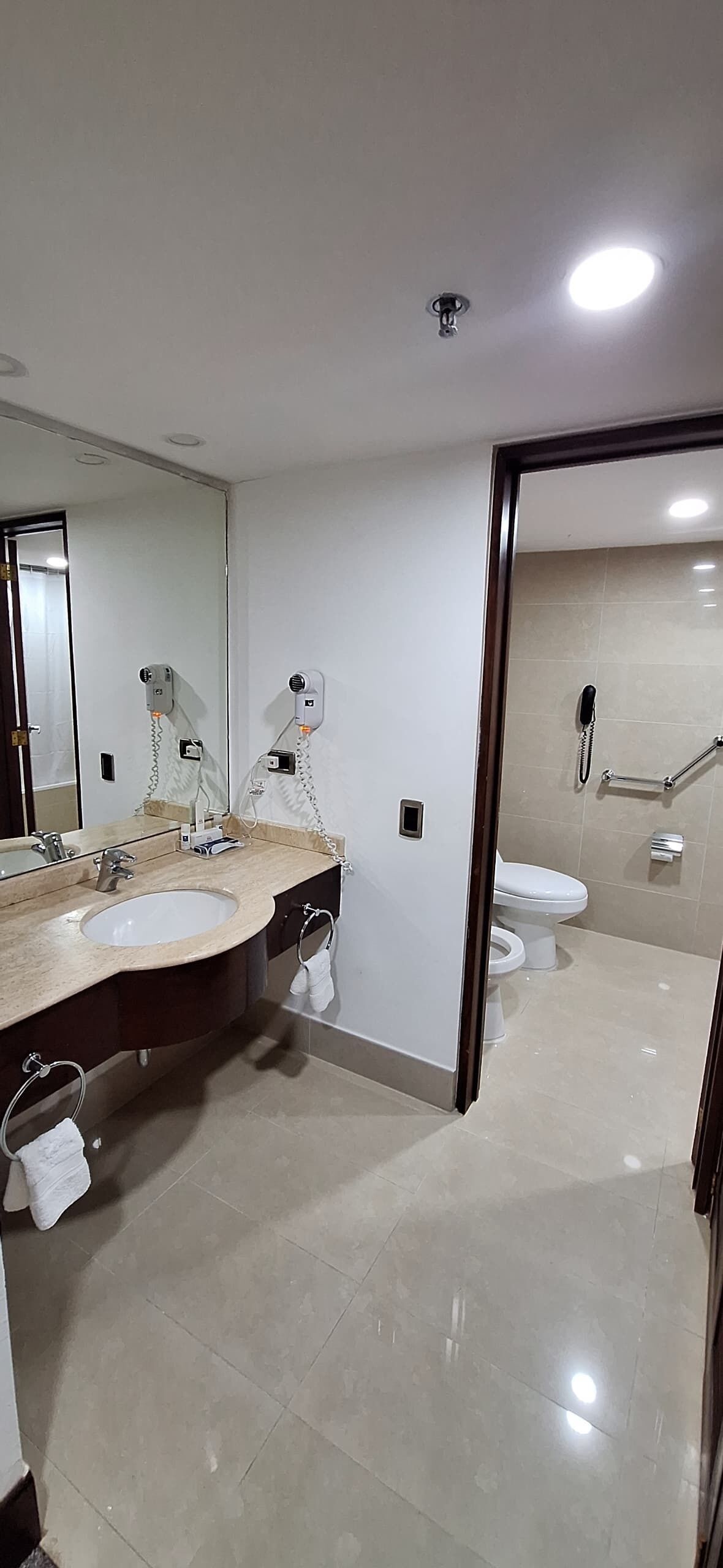 Un baño moderno con dos lavamanos, un espejo grande y un inodoro.