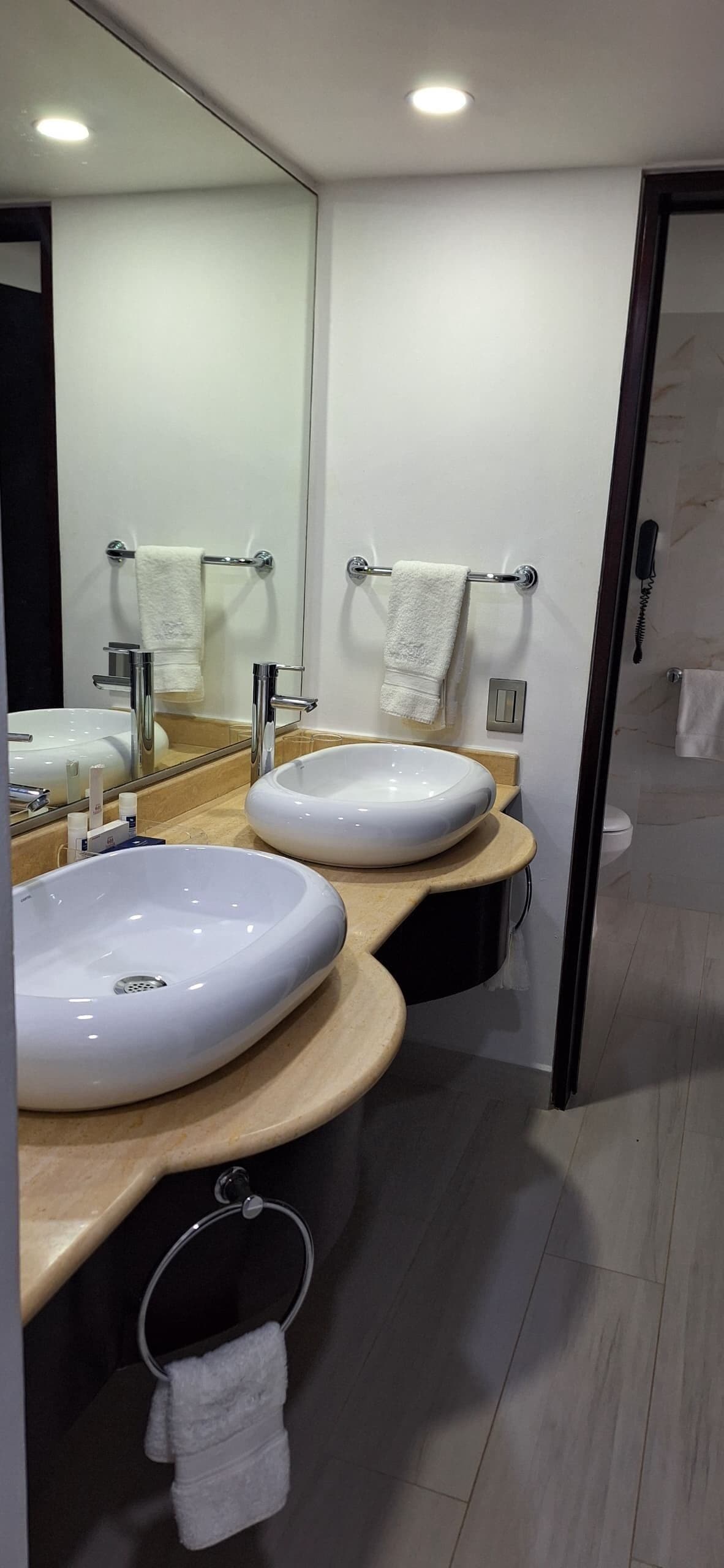 A modern bathroom with two white sinks, a large mirror, and a wooden vanity.