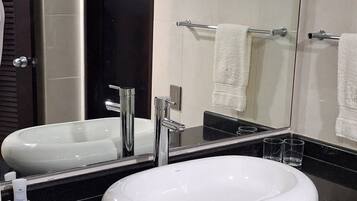 Une salle de bain moderne avec un grand miroir, deux lavabos, un porte-serviettes et une cabine de douche en verre.