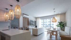 Een moderne keuken met een centraal eiland, een zithoek met tafel en stoelen, een bank en een groot raam met uitzicht.