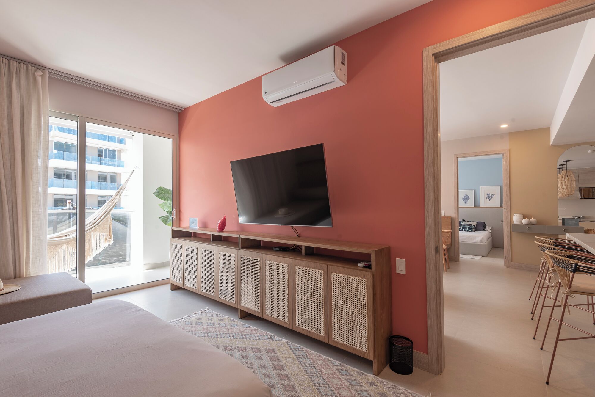 Une chambre moderne avec un grand lit, un téléviseur fixé au mur et un balcon offrant une vue sur la ville.