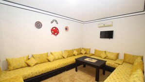 Un salon avec un canapé jaune, une table basse et des éléments décoratifs accrochés au mur.