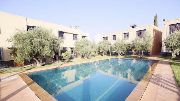 Une piscine rectangulaire à l’eau d’un bleu limpide, entourée d’une zone pavée et d’arbres.