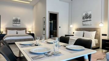 A modern hotel room with two beds, a dining table set for two, and artwork on the walls.