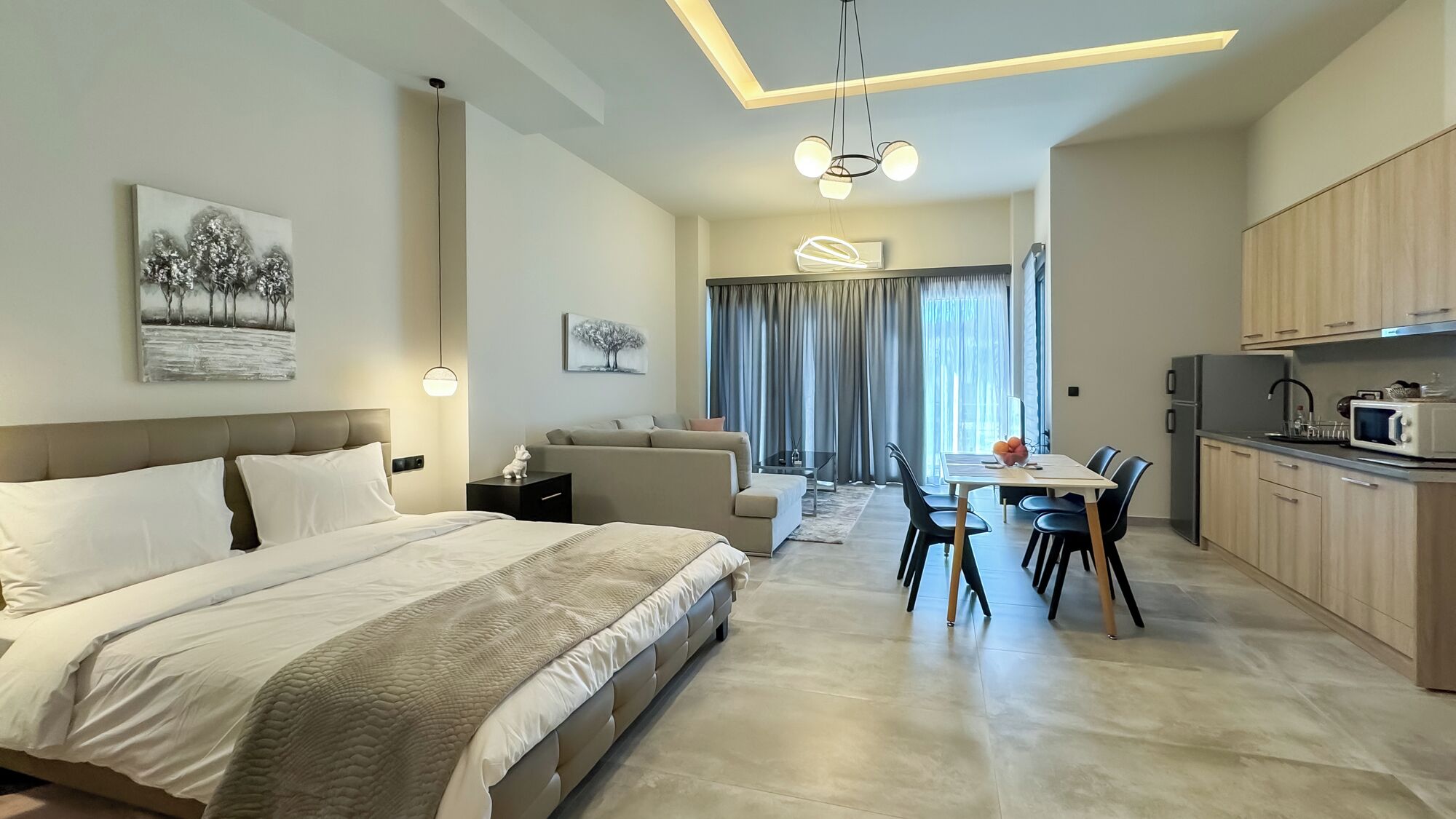 Une chambre d’hôtel moderne dotée d’un grand lit, d’un coin repas et d’une cuisine.