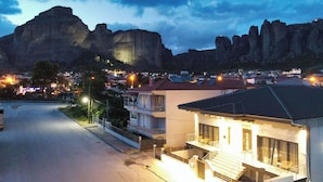 A residential area with a prominent mountain in the background, a street with houses, and a building with a balcony.