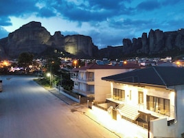 A residential area with a prominent mountain in the background, a street with houses, and a building with a balcony.