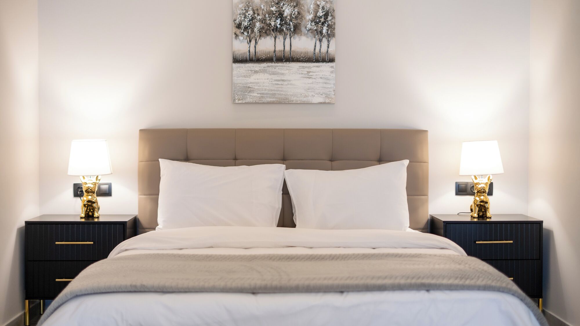 Une chambre à coucher avec un grand lit, deux tables de chevet avec des lampes et un tableau au mur.