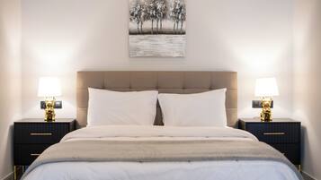 Une chambre à coucher avec un grand lit, deux tables de chevet avec des lampes et un tableau au mur.