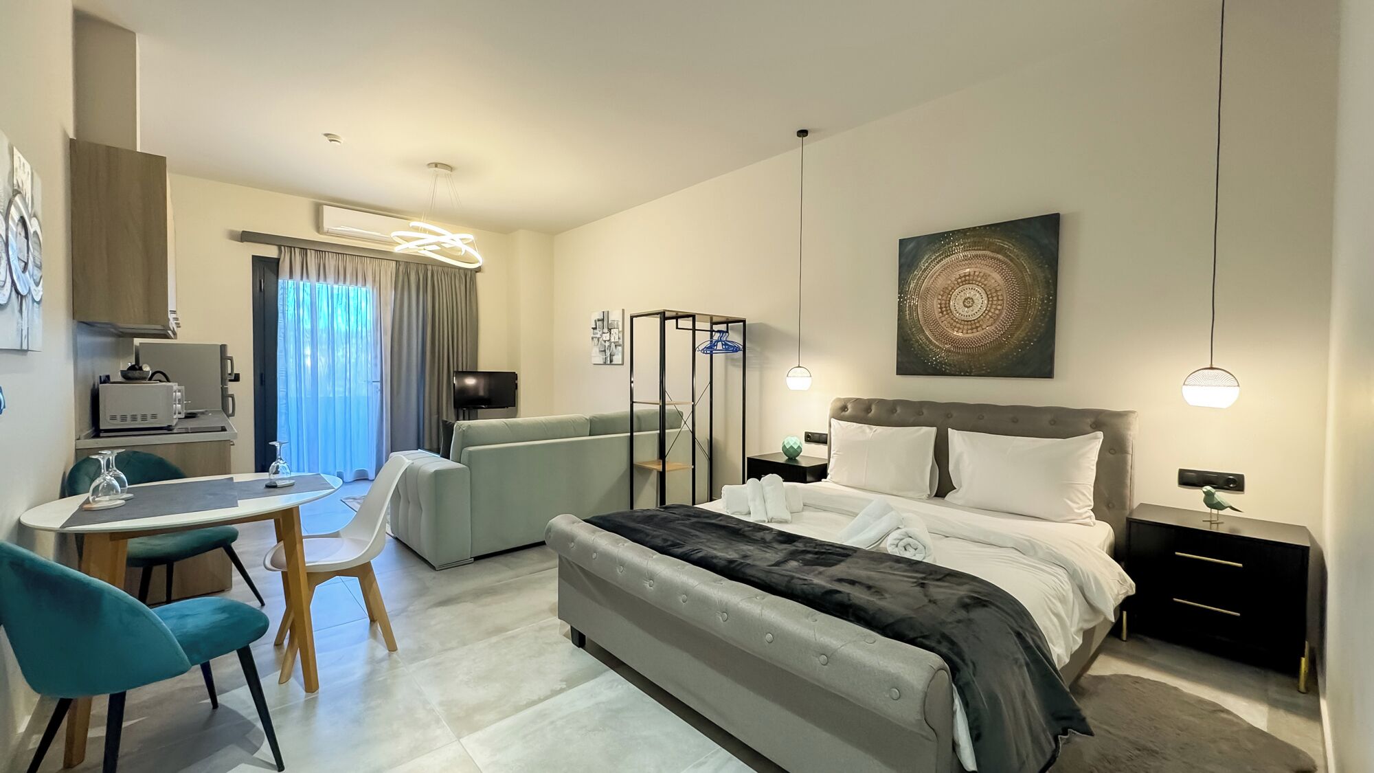 Una camera d'albergo moderna con un letto, una scrivania con una sedia, un divano e una televisione.